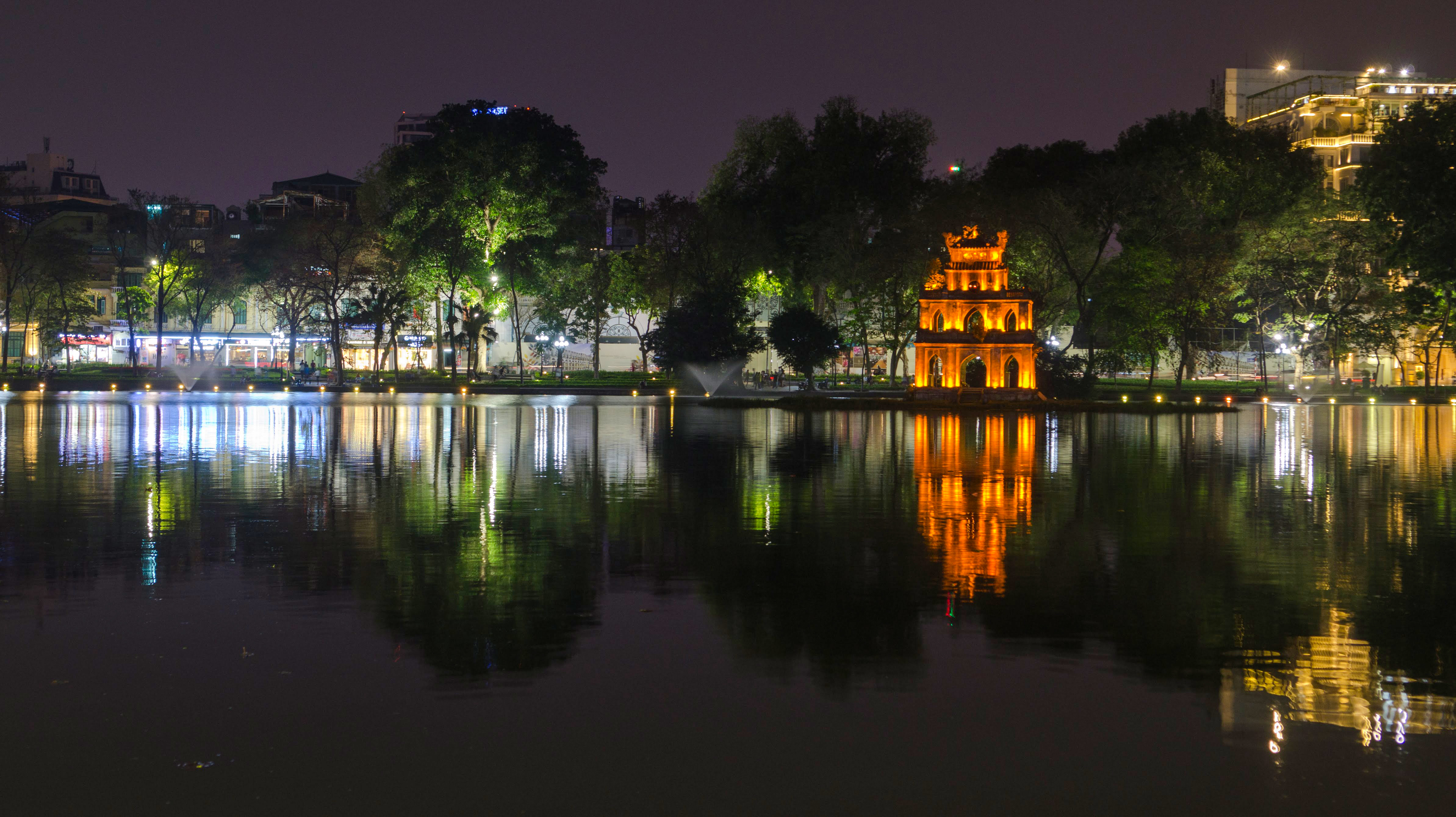 Voyage à moto au Vietnam : le lac Hoan Kiem en soirée Lac Hoan Kiem illuminé en soirée à Hanoi au Vietnam