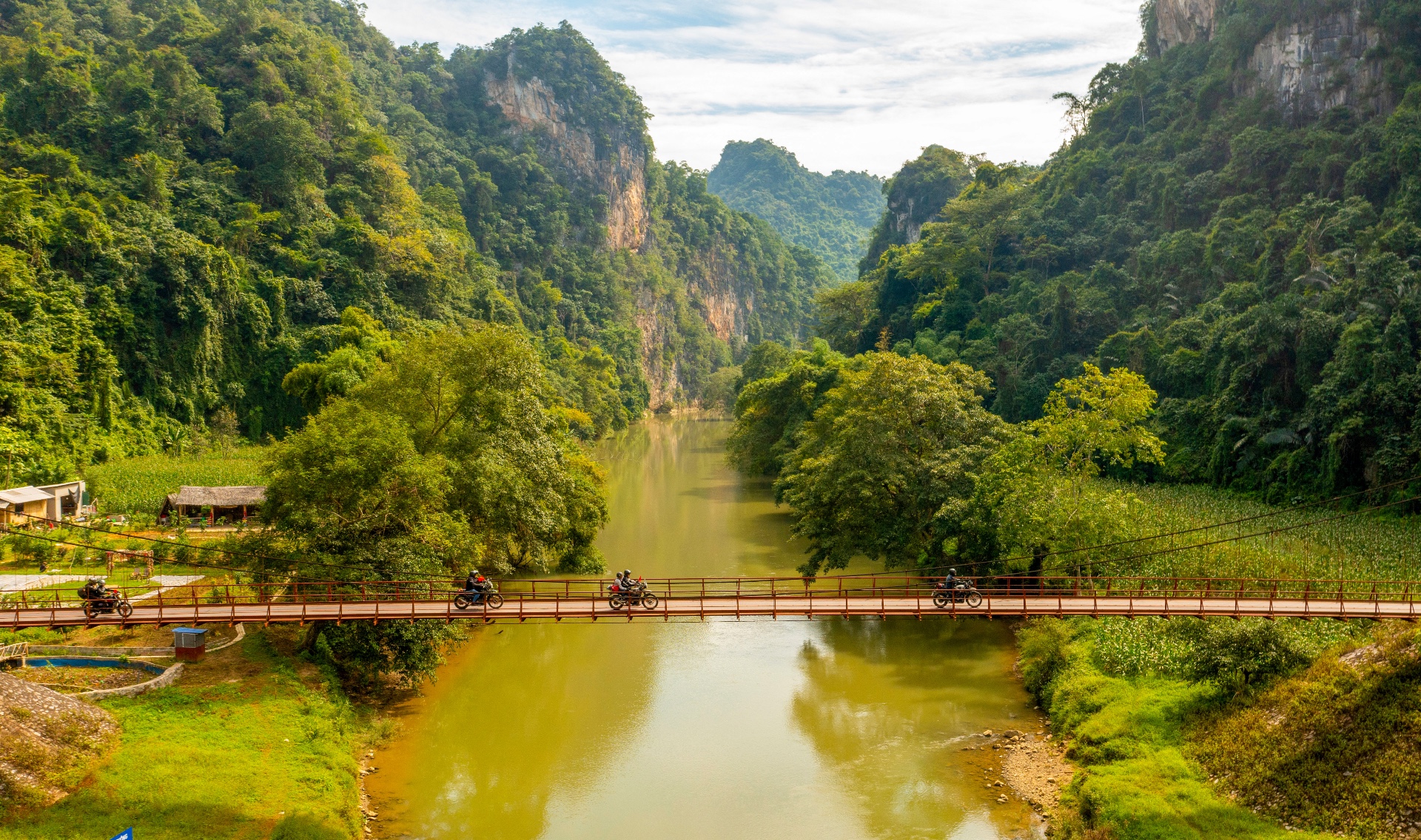 Motard traversant un pont suspendu à Ba Be Motard traversant un pont suspendu dans le Nord du Vietnam lors d’un Voyage à moto au Vietnam